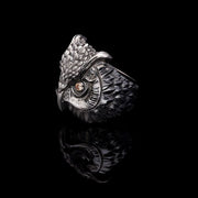 A men's sterling silver ring with an owl design on a dark background.